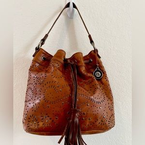 The Sak brown leather bucket bag perforated design tassel metal hangtag BoHo